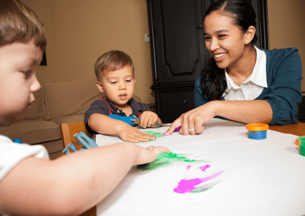 Children playing with paints whilst an adult is supervising
